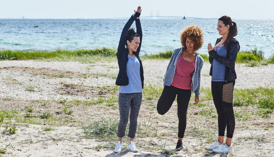 Three women exercising on a beach